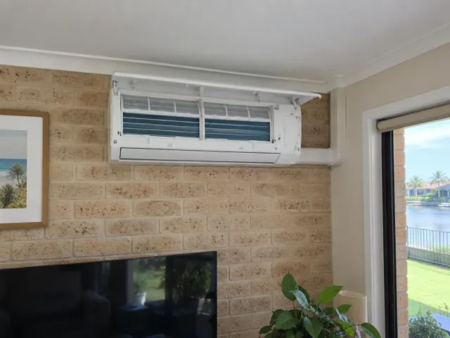 Clean split system with open front panel and visible filters on a brick internal wall in Hope Island