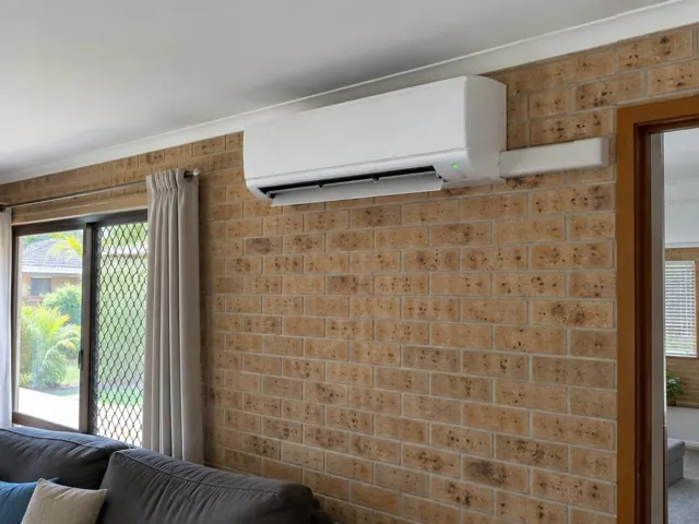 White split system running on a brick internal wall above a lounge room in Oxenford