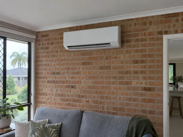 Wall-mounted split system on a brick living room wall above a sofa in Hope Island